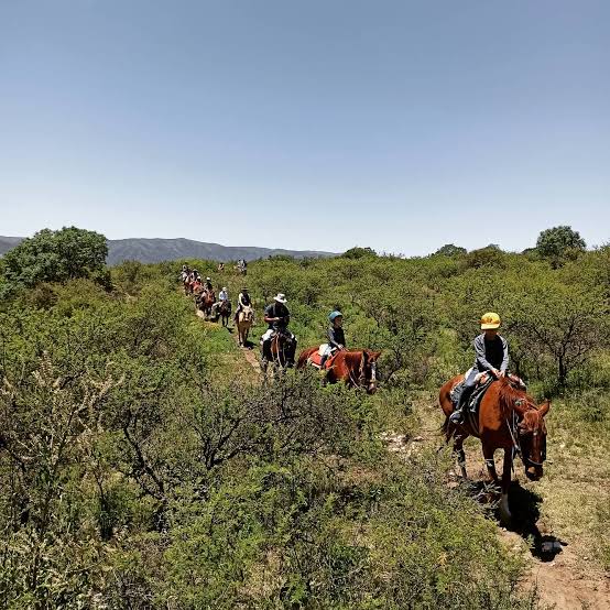 Grupo de personas cabalgando por un sendero serrano