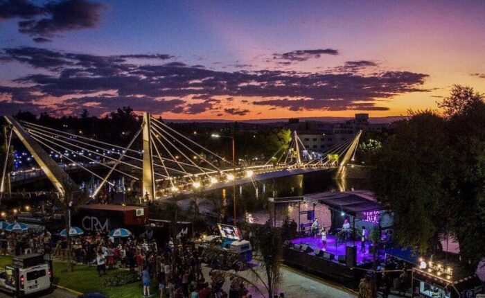 Puente iluminado al atardecer con un espectáculo en vivo junto al río